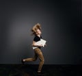 Young handsome guy in a black T-shirt with long blonde hair runs briskly holding an arrow in his hands on a gray background