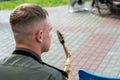 A young handsome guy with a saxophone in his hands. A military band, a musician in a military uniform holding an instrument. Wind Royalty Free Stock Photo