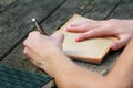 Young handsome guy sitting at wooden table, writing a book, doing homework, taking notes, learning, contemplating and writing. Royalty Free Stock Photo