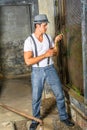 A young handsome guy is standing by a screen window inside a abandoned house,  looking at green leaves and into deeply thinking Royalty Free Stock Photo