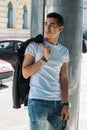 Young, handsome guy in a white T-shirt, black, leather jacket and blue, torn jeans is on the street, model, city walk, live style