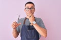 Young handsome hairdresser man wearing apron over pink isolated background cover mouth with hand shocked with shame for mistake,