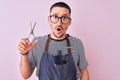 Young handsome hairdresser man wearing apron over pink isolated background scared in shock with a surprise face, afraid and Royalty Free Stock Photo