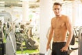 Young handsome half-naked man standing and holding towel in a gym Royalty Free Stock Photo