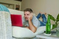 Young handsome happy man lying at home sofa couch working online with laptop computer using netbook relaxed comfortable with beer Royalty Free Stock Photo