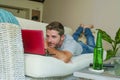 Young handsome happy man lying at home sofa couch working online with laptop computer using netbook relaxed comfortable with beer Royalty Free Stock Photo