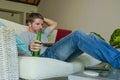 Young handsome happy man sitting at home sofa couch working online with laptop computer using netbook relaxed comfortable drinking Royalty Free Stock Photo