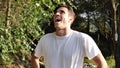 Young man doing evil laughter, outside in nature Royalty Free Stock Photo