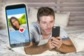 Young handsome and happy man using internet social media on mobile phone searching love flirting and dating online sending like to Royalty Free Stock Photo