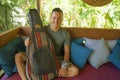 Young handsome and happy mixed ethnicity man in hipster style chilling outdoors with guitar relaxed at tranquil tropical garden Royalty Free Stock Photo