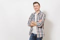 Young handsome happy smiling man in gray t-shirt, blue jeans, checkered shirt holding hands crossed over chest Royalty Free Stock Photo