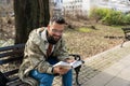 Young handsome hipster freelance business man wearing jacket reading a book while sitting outdoors. Businessperson on lunch break Royalty Free Stock Photo