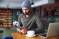 Young handsome hipster guy at the restaurant using a mobile phone. Royalty Free Stock Photo