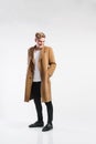 Young handsome hipster man in brown coat, studio shot.
