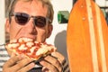 Young handsome hipster man eating a slice of pizza margherita