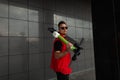 Young handsome hipster man with stylish hairstyle in sunglasses in a red denim trendy vest is resting standing with a scooter Royalty Free Stock Photo