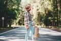 Young handsome hipster woman wearing hat and traveling backpack and stand on road Royalty Free Stock Photo