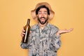 Young handsome hispanic bohemian hipster man with bear drinking from a empty wine bottle very happy and excited, winner expression