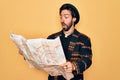 Young handsome hispanic bohemian hipster man with bear looking a tourist city map scared in shock with a surprise face, afraid and Royalty Free Stock Photo