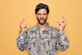Young handsome hispanic bohemian man wearing hippie style and sunglasses shouting with crazy expression doing rock symbol with Royalty Free Stock Photo