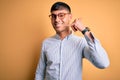Young handsome hispanic business man wearing nerd glasses over yellow background smiling doing phone gesture with hand and fingers Royalty Free Stock Photo