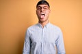 Young handsome hispanic business man wearing nerd glasses over yellow background sticking tongue out happy with funny expression Royalty Free Stock Photo