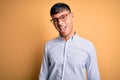 Young handsome hispanic business man wearing nerd glasses over yellow background winking looking at the camera with sexy Royalty Free Stock Photo