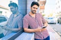 Young handsome hispanic man with beard smiling happy outdoors using smartphone Royalty Free Stock Photo