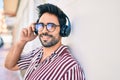 Young handsome hispanic man with beard smiling happy outdoors wearing headphones listening to music Royalty Free Stock Photo