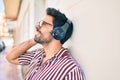 Young handsome hispanic man with beard smiling happy outdoors wearing headphones listening to music Royalty Free Stock Photo