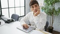 Young, handsome hispanic man deep in thought, working at his laptop in the office Ã¢â¬â a portrait of a serious yet relaxed Royalty Free Stock Photo