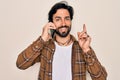 Young handsome hispanic man having a conversation talking on smartphone surprised with an idea or question pointing finger with Royalty Free Stock Photo