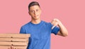 Young handsome hispanic man holding delivery pizza box with angry face, negative sign showing dislike with thumbs down, rejection Royalty Free Stock Photo