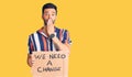 Young handsome hispanic man holding we need a change banner covering mouth with hand, shocked and afraid for mistake