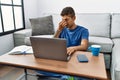 Young handsome hispanic man using laptop sitting on the floor tired rubbing nose and eyes feeling fatigue and headache Royalty Free Stock Photo