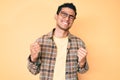 Young handsome hispanic man wearing casual clothes and glasses very happy and excited doing winner gesture with arms raised, Royalty Free Stock Photo