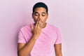 Young handsome hispanic man wearing casual pink t shirt bored yawning tired covering mouth with hand Royalty Free Stock Photo