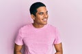 Young handsome hispanic man wearing casual pink t shirt looking away to side with smile on face, natural expression Royalty Free Stock Photo