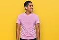 Young handsome hispanic man wearing casual pink t shirt looking away to side with smile on face, natural expression Royalty Free Stock Photo