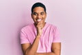 Young handsome hispanic man wearing casual pink t shirt looking confident at the camera with smile with crossed arms and hand Royalty Free Stock Photo