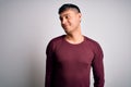 Young handsome hispanic man wearing casual shirt standing over white isolated background smiling looking to the side and staring Royalty Free Stock Photo