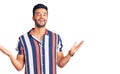 Young handsome hispanic man wearing casual  summer shirt celebrating victory with happy smile and winner expression with raised Royalty Free Stock Photo