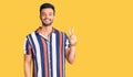 Young handsome hispanic man wearing casual  summer shirt smiling with happy face winking at the camera doing victory sign Royalty Free Stock Photo