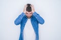 Young handsome hispanic man wearing denim jacket over white isolated background suffering from headache desperate and stressed Royalty Free Stock Photo