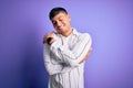 Young handsome hispanic man wearing elegant business shirt standing over purple background Hugging oneself happy and positive, Royalty Free Stock Photo