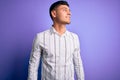 Young handsome hispanic man wearing elegant business shirt standing over purple background looking away to side with smile on Royalty Free Stock Photo