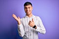 Young handsome hispanic man wearing elegant business shirt standing over purple background Showing palm hand and doing ok gesture Royalty Free Stock Photo