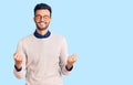 Young handsome hispanic man wearing elegant clothes and glasses excited for success with arms raised and eyes closed celebrating Royalty Free Stock Photo