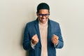Young handsome hispanic man wearing elegant clothes and glasses very happy and excited doing winner gesture with arms raised, Royalty Free Stock Photo