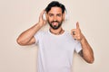 Young handsome hispanic man wearing headphones listening to music over isolated background happy with big smile doing ok sign, Royalty Free Stock Photo